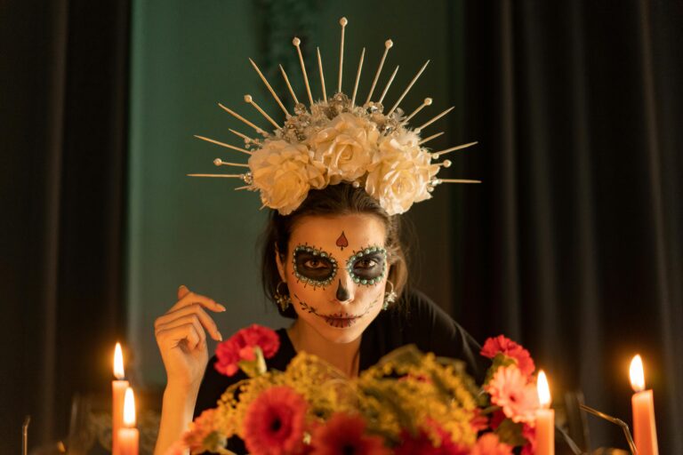 An artistic portrait of a woman with Dia de los Muertos makeup and floral crown, surrounded by candles.